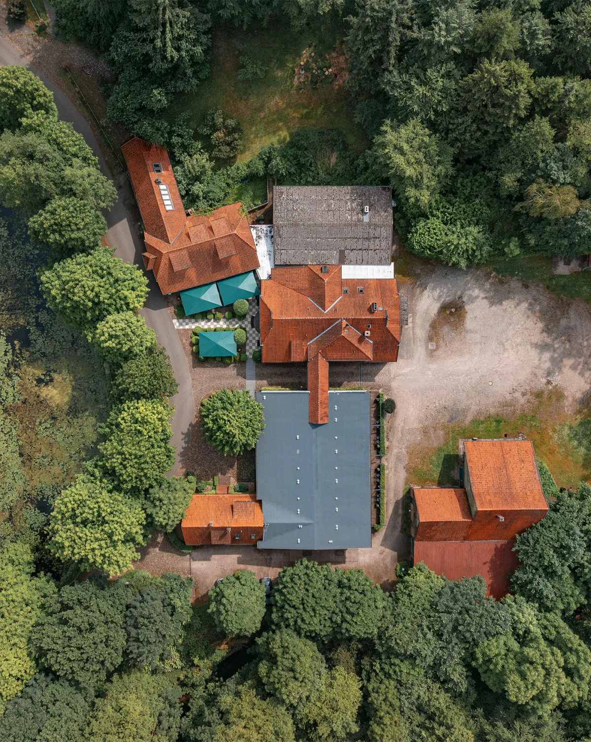 Luftaufnahme eines weitl&auml;ufigen Anwesens mit historischen Geb&auml;uden, umgeben von dichtem Wald.