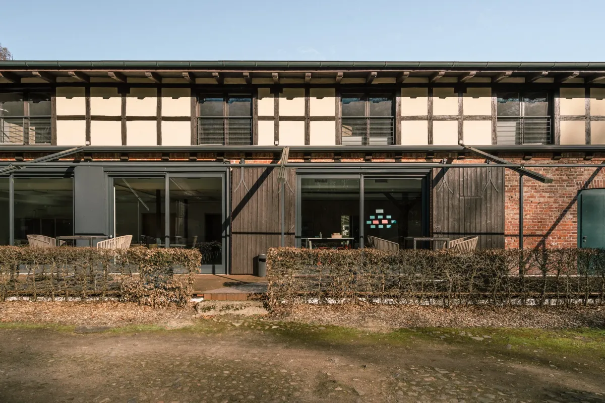 Moderne Eventlocation mit gro&szlig;z&uuml;gigen Glast&uuml;ren und Terrasse, rustikale Holz- und Backsteinarchitektur, umgeben von Natursteinen und gr&uuml;nem Rasen.