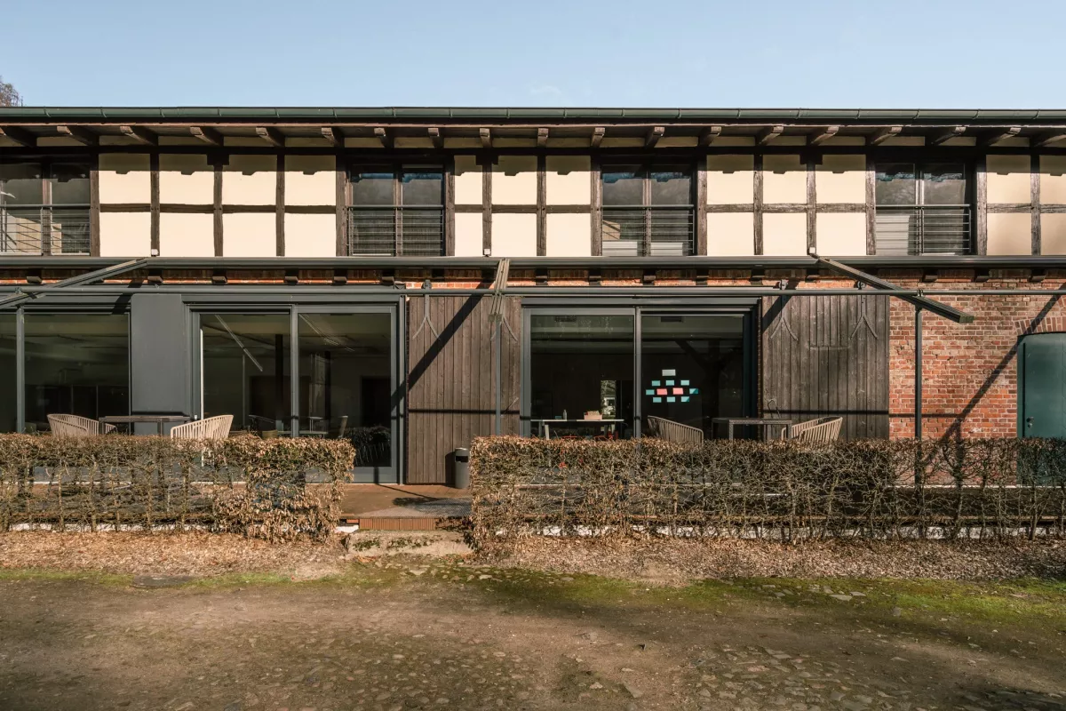 Moderne Eventlocation mit gro&szlig;z&uuml;gigen Glast&uuml;ren und Terrasse, rustikale Holz- und Backsteinarchitektur, umgeben von Natursteinen und gr&uuml;nem Rasen.