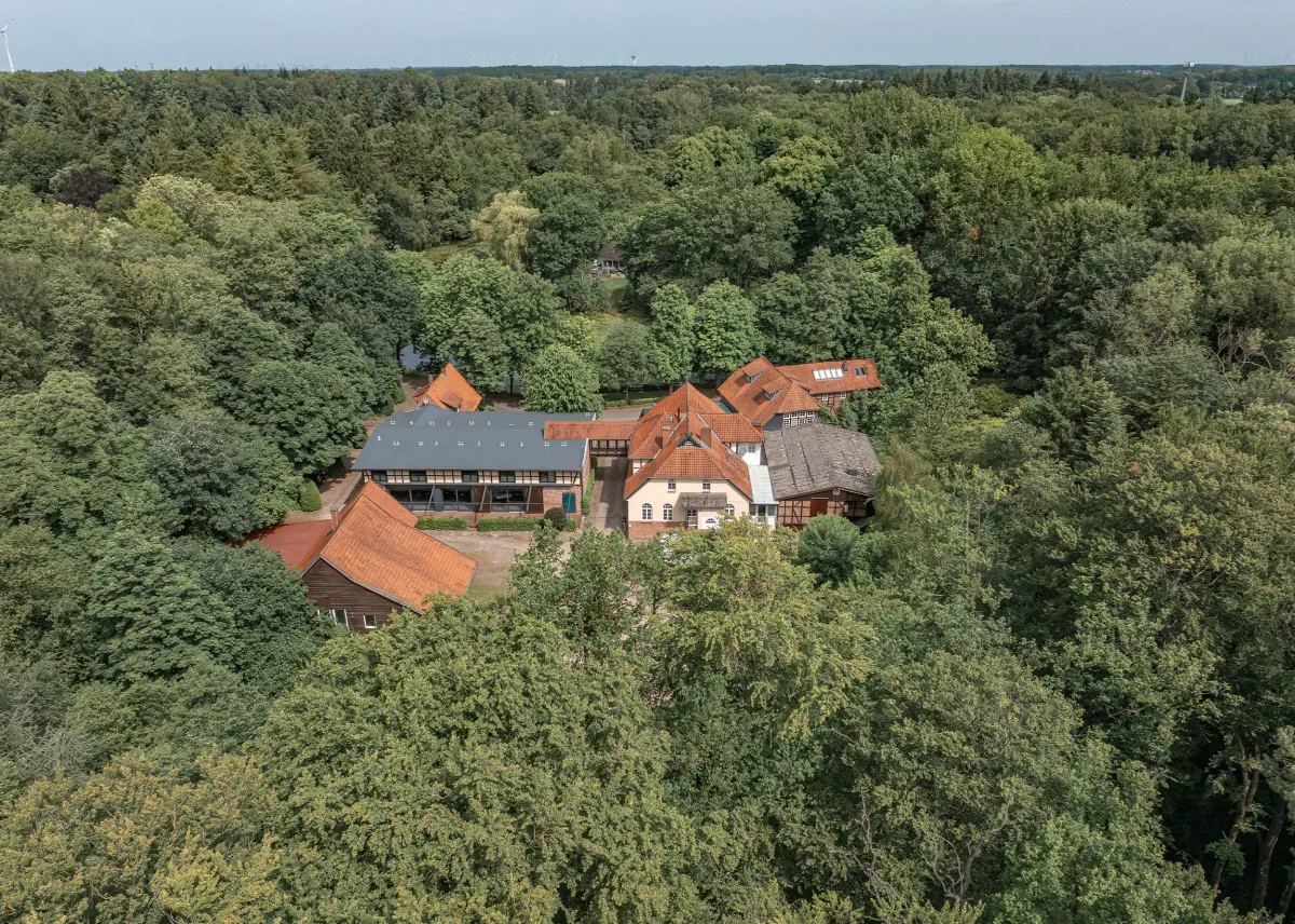 Luftaufnahme der Klosterm&uuml;hle mit mehreren Geb&auml;uden mit roten Ziegeld&auml;chern, umgeben von dichtem Wald und einem Weiher, ideal f&uuml;r Events und Feiern.