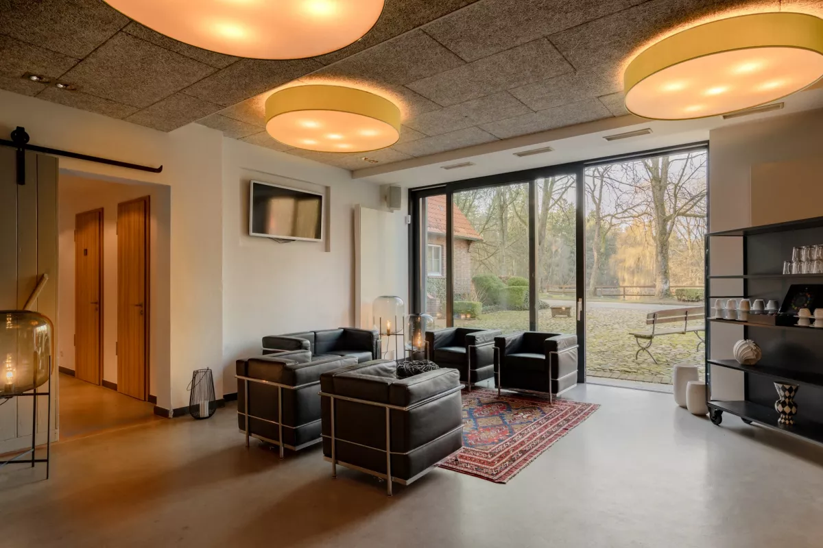 Modernes Foyer mit schwarzen Designm&ouml;beln, runden Deckenleuchten und gro&szlig;er Fensterfront zum Garten.